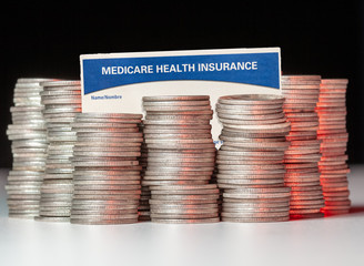 Many stacks of old silver dimes with medicare health insurance card to illustrate budget debt funding issues of the popular program © steheap