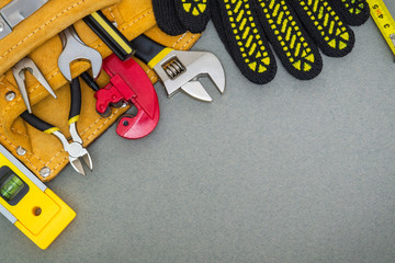 Building tools in the bag and work gloves on gray desktop are used to replace or repair