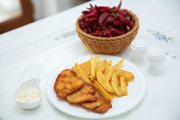 Fried chicken cutlet. Fry the potatoes in a white plate . Red Dry Pepper in Traditional Basket . Mayonnaise inside a bowl .