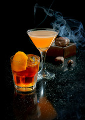 Strong alcoholic cocktails and smoke on a black background
