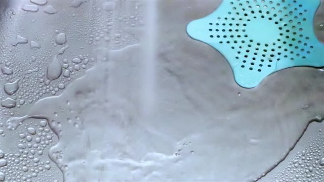 Running tap water drops in metal steel sink close-up video 