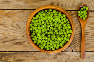 Fototapeta na wymiar Wooden bowl with canned green peas on table.