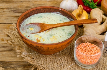 Vegetable soup with lentils in clay bowl on table