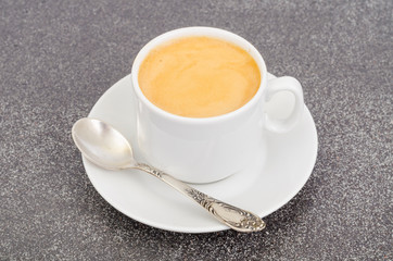 White cup espresso with foam on gray stone background.