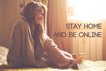 woman sitting in bed with digital tablet touching with finger in morning sunlight