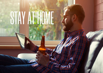 bearded man with digital tablet drinking bottle of beer