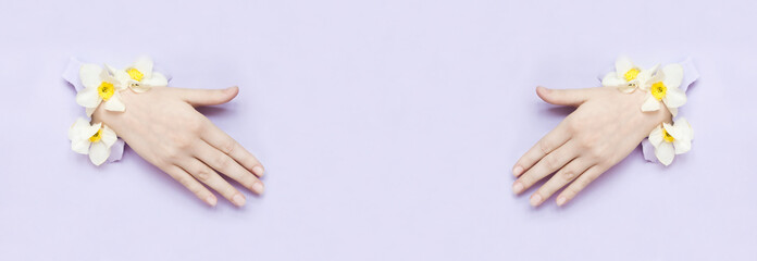 Cosmetics and hand care, moisturizing and wrinkle reduction.
Hands with torn paper flowers and painted nails is thrust through a hole.