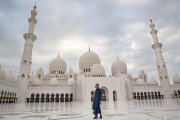 Fototapeta premium a girl in front of a mosque in Abu Dhabi under a palm tree UAE
