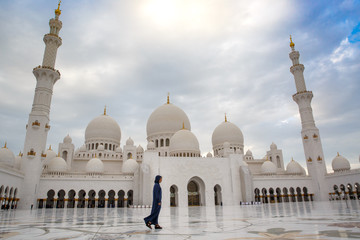 Fototapeta premium a girl in front of a mosque in Abu Dhabi under a palm tree UAE