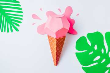 Summer background made of pink origami paper ice cream and paper tropical leaves. Minimal creative concept.