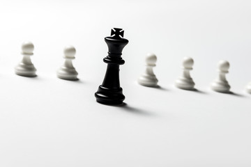 chess king is standing against white pawns. Symbol of leadership and confrontation. Horizontal frame