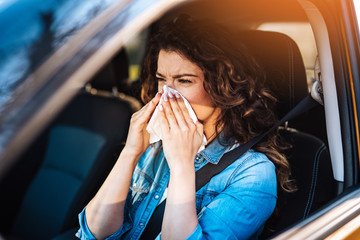 Young woman driving car with protective mask on her face.  Healthcare, virus protection, allergy...