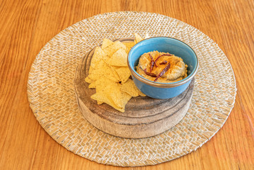 hummus with chips in blue bowl on wooden board