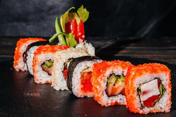 Beautiful and delicious variety of sushi rolls laid out on a stone board.
