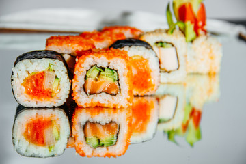 Beautiful sushi set on laid out on a mirrored table, the background is blurred