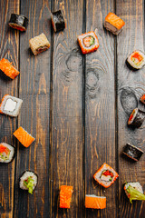 Sushi rolls laid out on a wooden dark table, in the center of copyspace