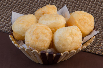 Lush fresh donuts made of wheat flour fried in aromatic vegetable oil lie in a wooden basket on a brown background
