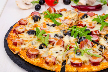 Tasty pizza with salami, mozzarella, mushrooms and olives on wooden background.