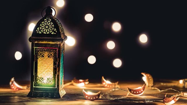 Ramadan Lantern with Colorful Light Glowing at Night and Glittering with Bokeh Lights on Ground. Festive Greeting Card, Invitation for Muslim Holy Month Ramadan Kareem. Dark background