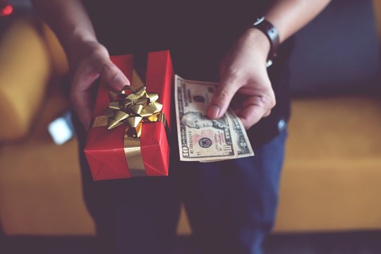 Midsection Of Man Holding Christmas Present With Money At Home
