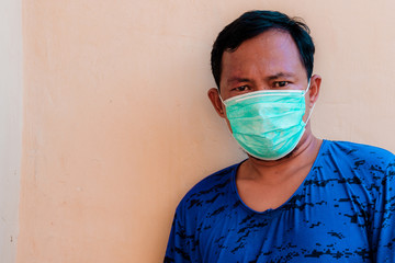 Asian man wearing face mask is showing head ache expression. The concept of people having to wear masks in public during  a COVID-19 pandemic or coronavirus disease crisis.