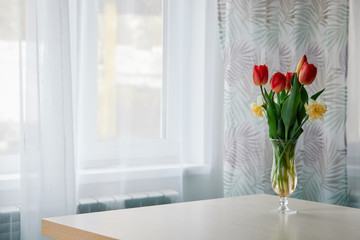 Spring tulips in a glass vase on the table