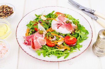 Fresh homemade salad with arugula, jamon, rucola, tomatoes, parmesan.