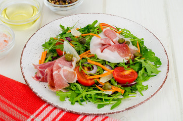Plate with fresh salad leaves, parmesan slices and jamon. Studio Photo