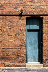 Blue door with threshold and arched passthrough set in lovely yellow and brown brick wall in ally