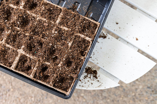 Top View Of Seed Starter Kit Filled With Soil On White Wood Table