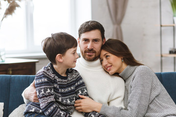 Portrait of smiling father, mother and son. Happy family spending time together at home. Cute boy with mom and dad playing at home. Time to family leisure. Family values.