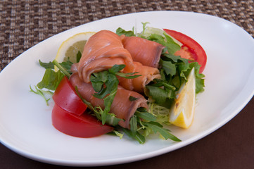 Salmon rolls stuffed with various herbs, tomato and lemon slices for decoration
