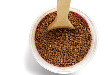 buckwheat in a plastic jar. wooden spoon in buckwheat.