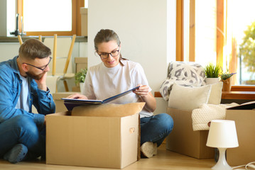 Happy young couple unpacking or packing boxes and moving into a new home