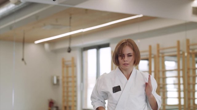 Young woman practising karate indoors in gym.