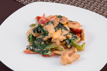Chicken breast salad with vegetables seasoned with sour cream sauce on a white plate
