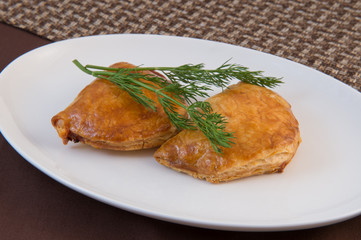 Georgian Khachapuri. Baked puff pastry pie with cheese on a white oval plate with a sprig of dill.
