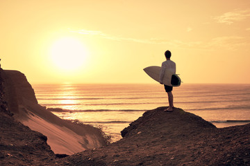 A surfer looks left over the sur fbreak during sunset
