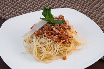 Italian spaghetti with spicy sweet carrot gravy, grated cheese, a sprig of mint, and slices of cheese