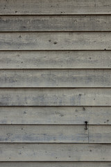 Wooden siding wall with a tan grey finish and a few knots vertical
