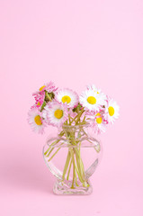 Pink background for valentines day card, vase with flowers in shape of heart.