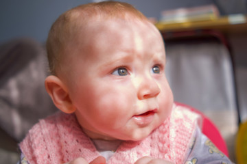 Cute little baby girl sitting in the baby walker and looking around