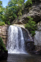 Fototapeta premium Beautiful summer landscape with a waterfall. A large waterfall among the huge cliffs overgrown with trees. Looking Glass Fall, NC, USA