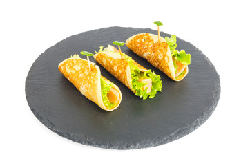 Pancake rolls with fish and lettuce. Salmon bread roll with cheese. On black stone plate.