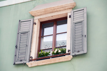 Italian window on the green color wall facade with open wooden green shutters