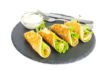 Pancake rolls with fish and lettuce. Salmon bread roll with cheese. On black stone plate.