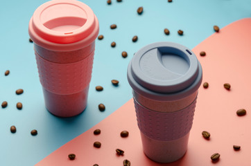 Reusable bamboo coffee cup with silicone holder on colorful background. Flat lay, copy space.