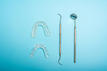 Dentist tools to avoid bruxism, arranged on a blue background seen from above.