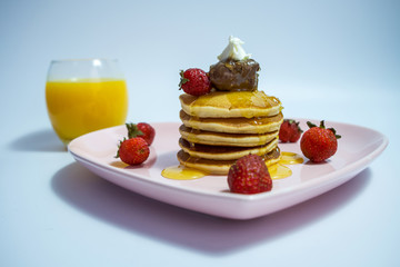 Close-up of stack of delicious fluffy pancakes with fresh strawberries and sugar and honey