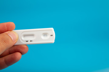 Man hand with holding Pregnant test kit on blue background.